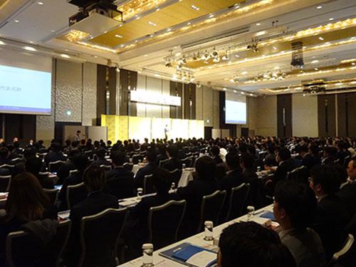 あいさつする高松社長（写真上）と「ブルーコンシャスグループ総決起集会」会場の様子